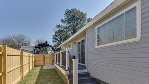 Een gelijkvloers huis met een veranda, een kleine voortuin en een houten omheining.