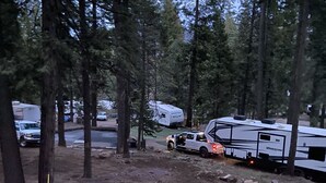 A campsite with RVs, a grassy area, and a blue chair. - Lake Almanor Peninsula Cabin In The Pines (Westwood)