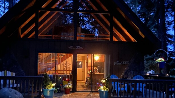 A log cabin with a wooden exterior, large windows, and a porch with potted plants. - Lake Almanor Peninsula Cabin In The Pines (Westwood)