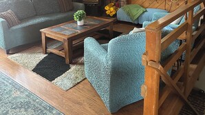 A cozy living room with a fireplace, wooden beams, a television, and comfortable seating. - Lake Almanor Peninsula Cabin In The Pines (Westwood)