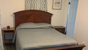 Een slaapkamer met een houten bed, een plafondventilator en een deur.