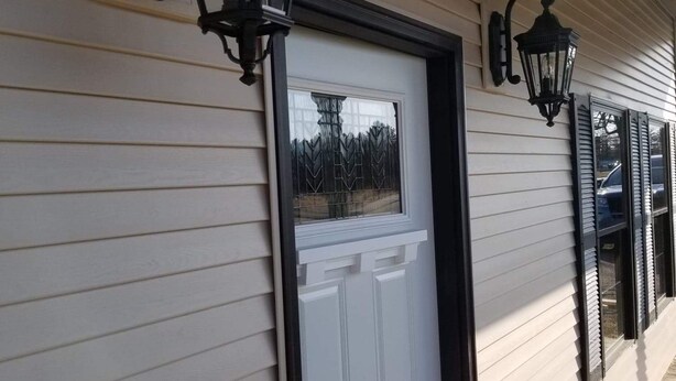 A white door with a black frame, flanked by two black lantern-style lights on the exterior wall. - Fully renovated 3 bed, 2 bath home (Grand Marais)