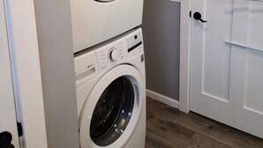 A laundry room with two stacked front-loading washing machines and a white door. - Fully renovated 3 bed, 2 bath home (Grand Marais)
