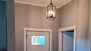 A hallway with a white door, a black mat at the entrance, and a hanging light fixture. - Fully renovated 3 bed, 2 bath home (Grand Marais)
