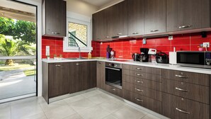 Una cocina moderna con armarios de madera oscura, un salpicadero de baldosas rojas y electrodomésticos de acero inoxidable.