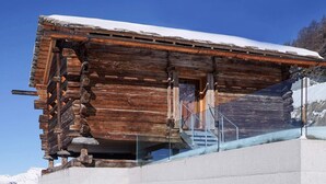 A modern log cabin with a glass balcony, large windows, and a snowy mountain backdrop. - Exclusive architectural chalet at 1,600 metres, 4-6 pers. in impressive location (Suen)
