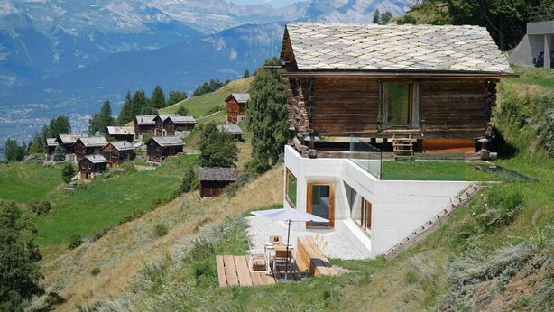 A modern chalet with a stone roof, wooden exterior, and a glass extension, surrounded by a mountainous landscape. - Exclusive architectural chalet at 1,600 metres, 4-6 pers. in impressive location (Suen)