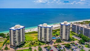 A high-rise hotel with multiple floors, a beach view, and a parking area with several cars. - Welcome to the paradises 
Departure clean included. Adv. #034724w10370b (Fort Myers Beach)