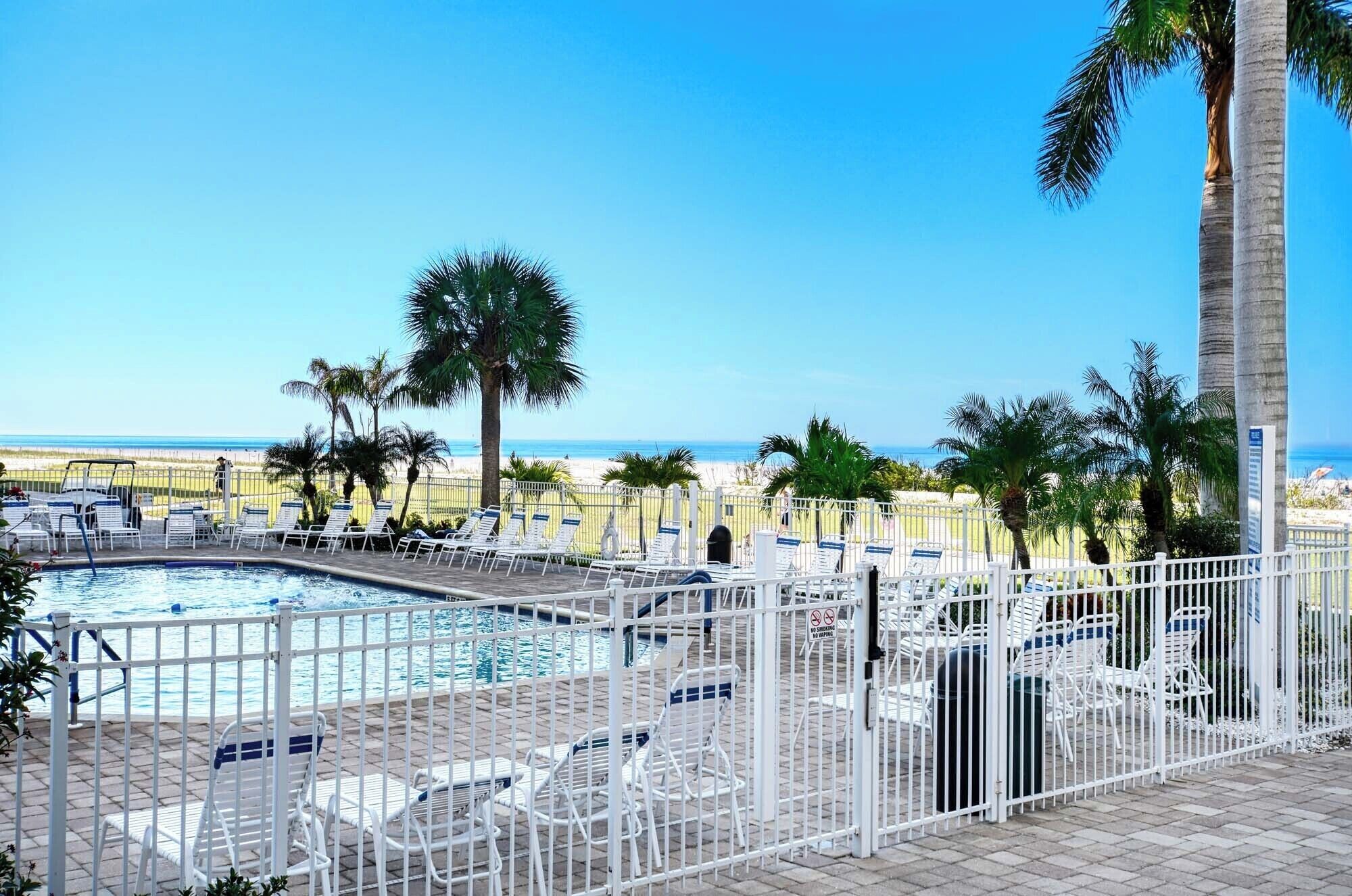 A pool area with lounge chairs and a view of the beach.