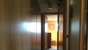 A narrow hallway with wooden walls and a carpeted floor, leading to a room with a door and a light fixture on the ceiling. - Montana Adventure (Dillon)