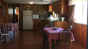 A spacious kitchen with wooden cabinets, a refrigerator, microwave, and a dining area with a table and chairs. - Montana Adventure (Dillon)
