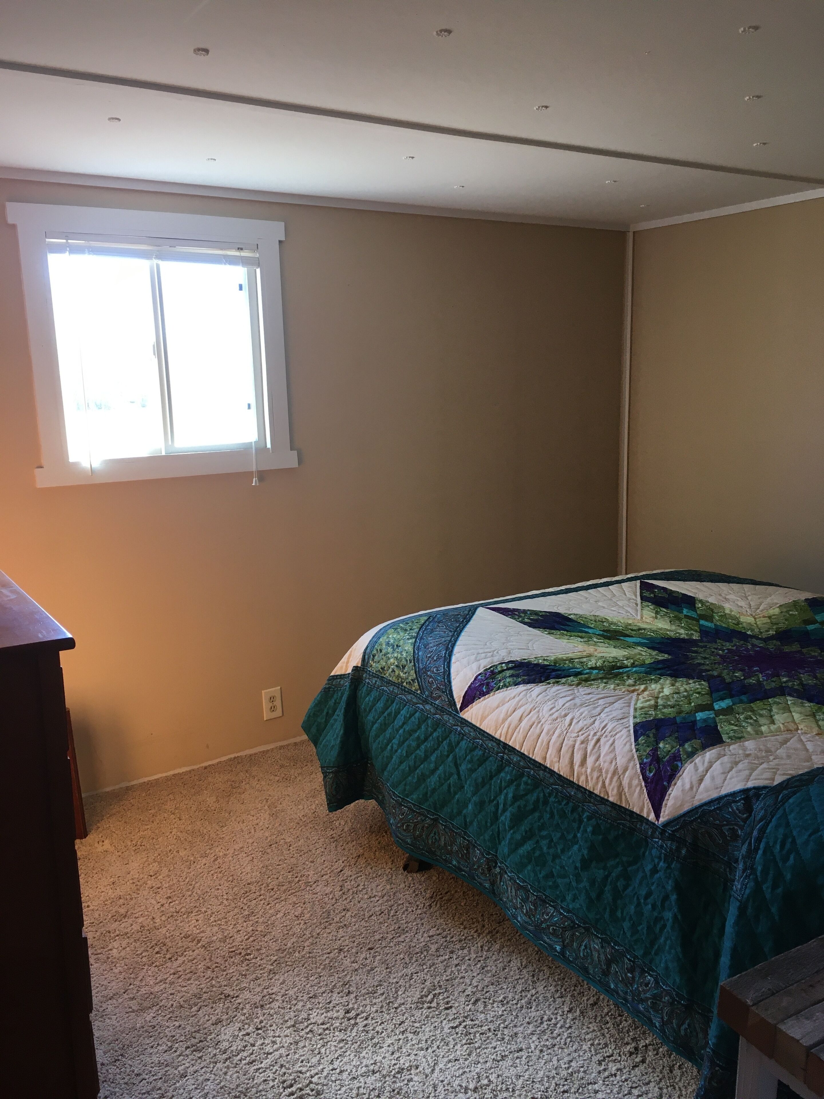 Un dormitorio con cama, ventana y cómoda.