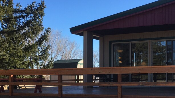 A building with a red roof and large windows, a wooden deck, and a snow-covered ground. - Montana Adventure (Dillon)