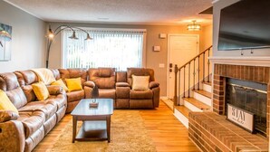 A living room with a brown leather sofa, a wooden coffee table, and a fireplace. - Suite 104 in Madison.... “Stay Awhile” (Madison)