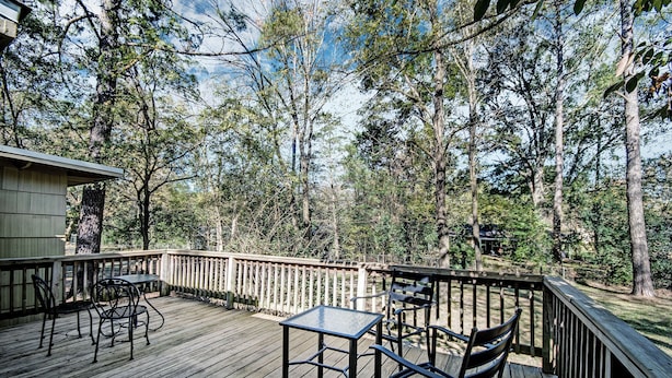 A wooden deck with a table and chairs, surrounded by trees. - Relax in Shady Oaks Near Hospitals & Dining (Jackson)