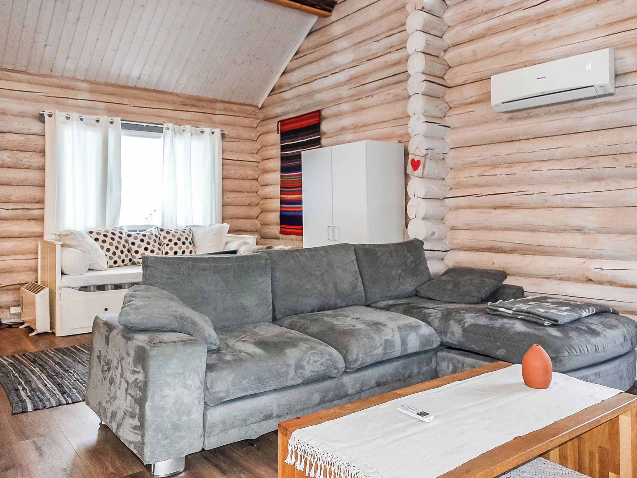 A cozy living room with a grey sofa, a white cabinet, and a wooden wall.