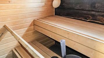 A sauna room with wooden benches and a black sauna floor.