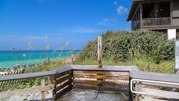 A wooden deck leading to a beach with a clear view of the ocean.