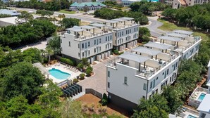 Un moderno complejo de apartamentos con varias construcciones, una piscina y vista al océano.
