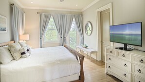 Un dormitorio con una cama, un aparador, un televisor y una ventana con cortinas.