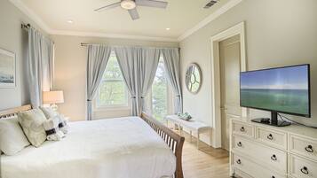 A bedroom with a bed, a dresser, a television, and a window with curtains.