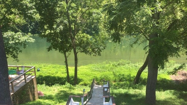 A wooden deck leading to a body of water surrounded by trees.