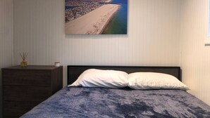 Un dormitorio con cama, cómoda y un cuadro de una playa.