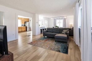 A modern living room with a grey sectional sofa, a flat-screen TV, and a colorful rug. - Keweenaw Trail Gateway (Calumet Township)