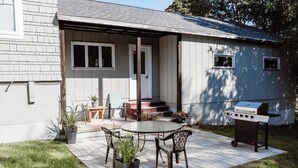 Une terrasse avec une table et des chaises, un barbecue et des plantes en pot.