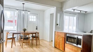 Une cuisine moderne avec un plancher en bois, un coin repas avec une table et des chaises, et un four encastré.