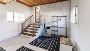 Une pièce spacieuse avec un escalier en bois, des murs en briques blanches et un tapis rayé noir et blanc.
