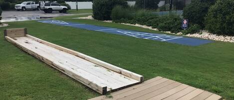 A grassy area with a wooden ramp leading to a blue handicap parking space.