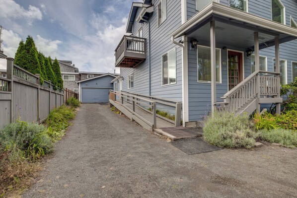A residential street with houses, a gravel driveway, and a wooden fence. - Relaxing Lincoln City Coastal Escape Near Beach! (Lincoln City)