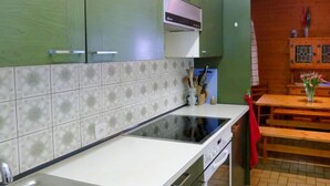 Una cocina con gabinetes verdes, encimera blanca, pileta de acero inoxidable y horno empotrado.