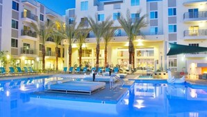 A hotel with a swimming pool, palm trees, and multiple balconies. - Luxury King -TPC Shops Dining Close S200 (Phoenix)