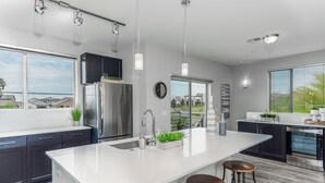 A modern kitchen with a large island, stainless steel appliances, and a view of the neighborhood. - Luxury King -TPC Shops Dining Close S200 (Phoenix)