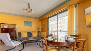 Una sala de estar con una mesa de comedor lista para cuatro personas, un sofá, una silla y un radiador.