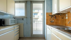 Una cocina compacta con horno empotrado, microondas y pileta.