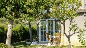 A garden with a stone pathway leading to a glass-enclosed patio area with outdoor furniture. - Beautiful private villa for 13 guests with A/C, private pool, WIFI, TV and patio (Alcover)