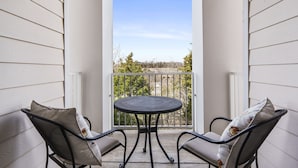 A balcony with two chairs and a table, offering a view of trees and a clear sky. - Spacious Branson Condo w/Pool, Elevator & Great Location Near All Attractions! (Branson)