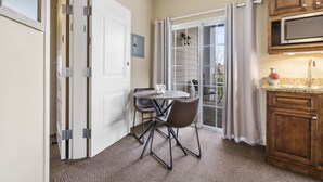 A compact kitchen with a dining area, a sliding glass door to a balcony, and wooden cabinets. - Spacious Branson Condo w/Pool, Elevator & Great Location Near All Attractions! (Branson)