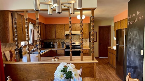 A modern kitchen with wooden cabinetry, a central island, and a dining area with a wooden table and chairs. - Country home with no pet fees!!  (Hillsboro)