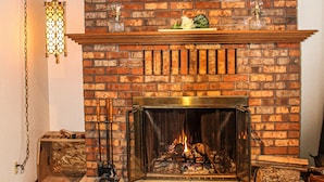 A brick fireplace with a mantel shelf, a hanging lantern, and a fire burning. - Country home with no pet fees!!  (Hillsboro)
