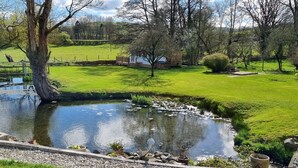 A serene garden with a pond, a wooden deck, and a stone pathway.