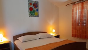 A neatly made bed with a wooden headboard, two bedside tables with lamps, and a colorful abstract painting on the wall. - A 4 apt w big terrace, sea view & close to beach (Arbanija)
