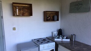 Una cocina compacta con estufa a gas, un refrigerador pequeño y una cafetera sobre la encimera.