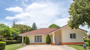 Ein eingeschossiges Haus mit Ziegeldach, einer überdachten Veranda und einer gepflasterten Auffahrt.