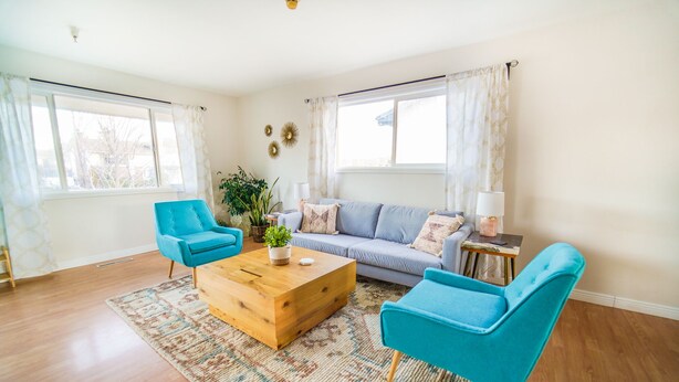 A living room with a sofa, two blue armchairs, a wooden coffee table, and a patterned rug. - Spacious Duplex with 3 King Beds ★ Conveniently Located Near AFA (Colorado Springs)