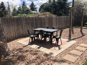 Eine Terrasse mit Tisch und Stühlen, umgeben von einem Holzzaun und einem Kiesweg.