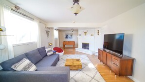 A living room with a sofa, a coffee table, a TV, and a fireplace. - Spacious Duplex with 3 King Beds ★ Conveniently Located Near AFA (Colorado Springs)